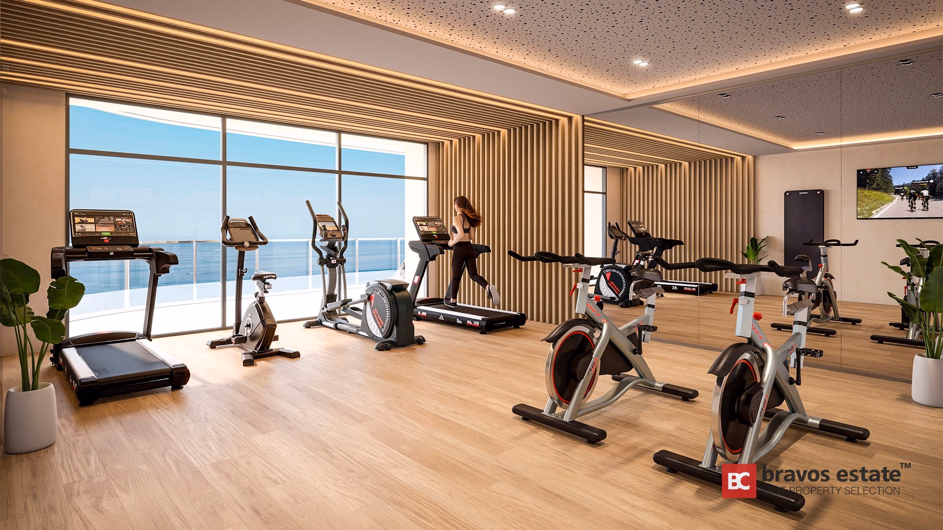 Sala de fitness del TM Tower con bicicletas de spinning, cintas de correr, pared de lamas de madera y vistas al mar