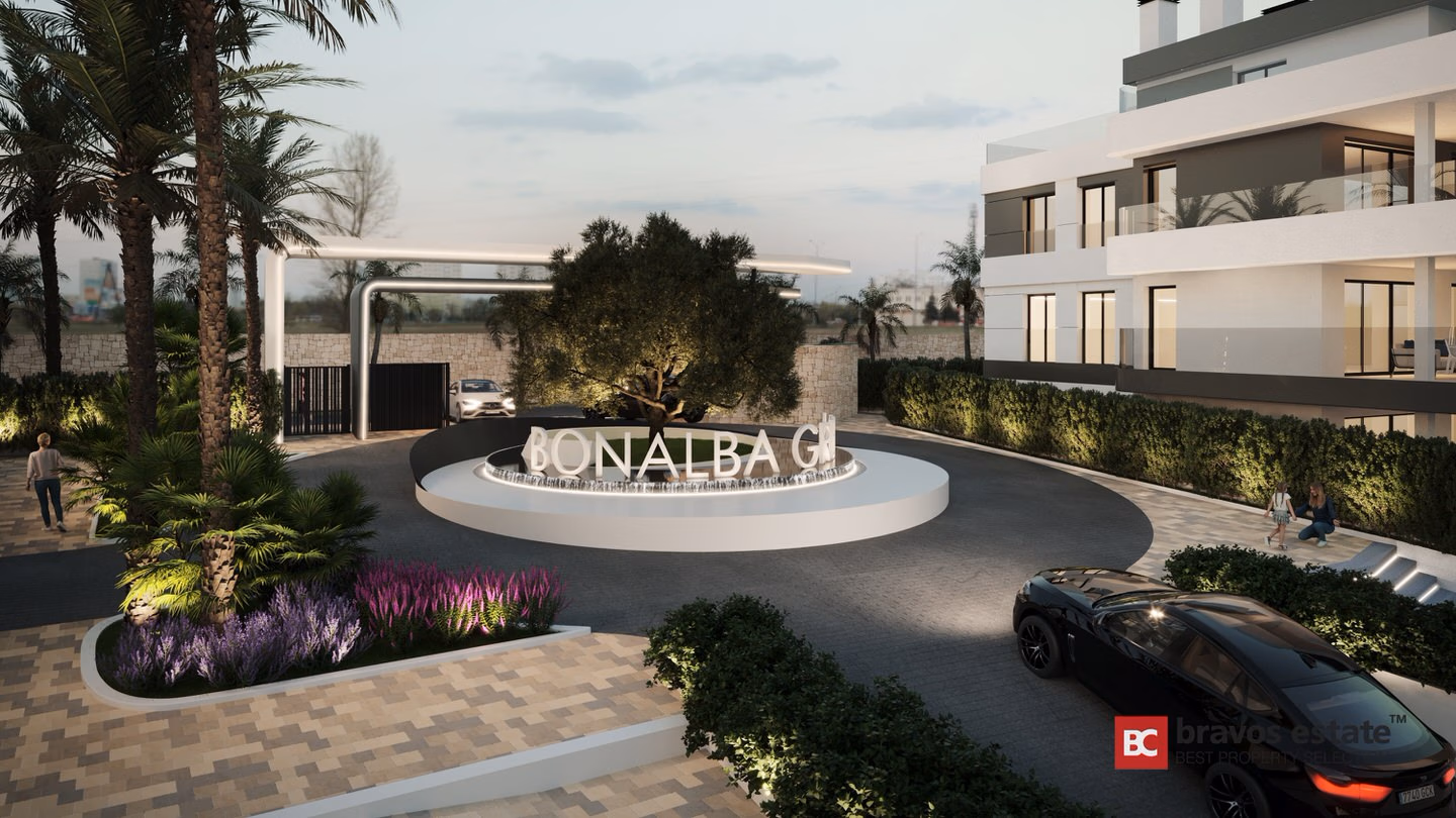 CGI render of Bonalba Green's illuminated entrance roundabout with branded centrepiece, gated access, palm-lined landscaping, and the white modern apartment building at dusk.