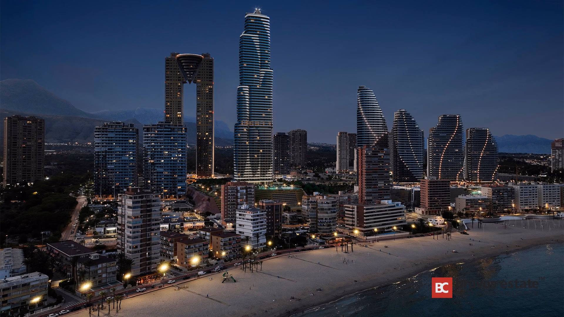 Horizonte nocturno de Playa de Poniente con TM Tower iluminado, playa de arena y montañas al fondo